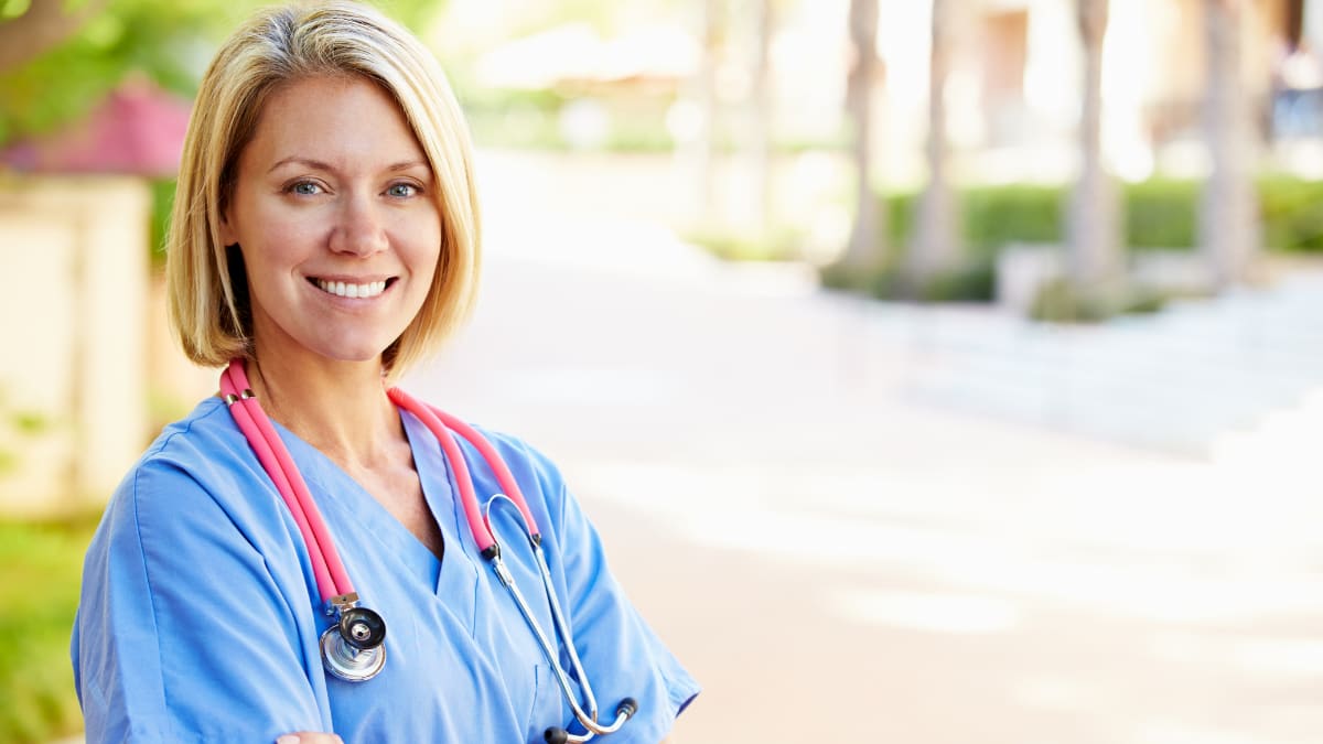 Female nurse standing outside with arms folded