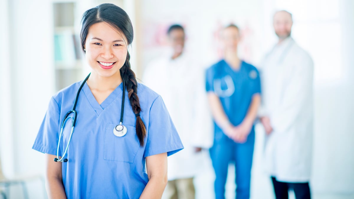 Happy nurse standing in front of doctors