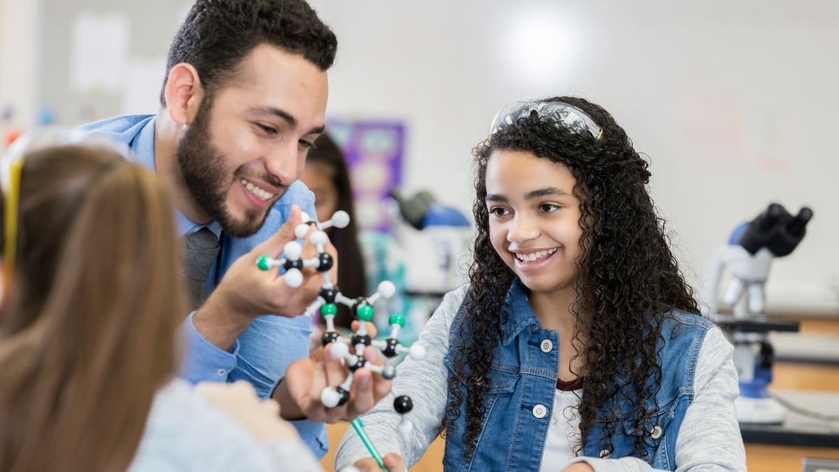 Male teacher teaching science to children