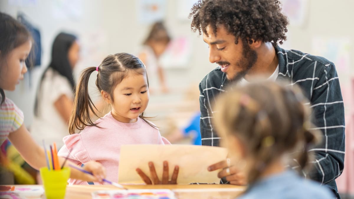 Male teacher teaching children art