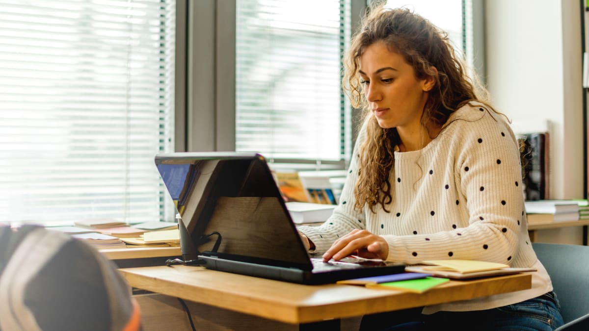 Woman working on laptop next to a window