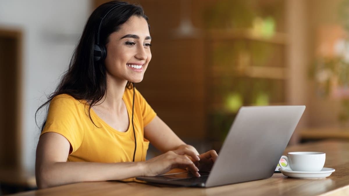 Smiling woman on a laptop with a cup of coffee