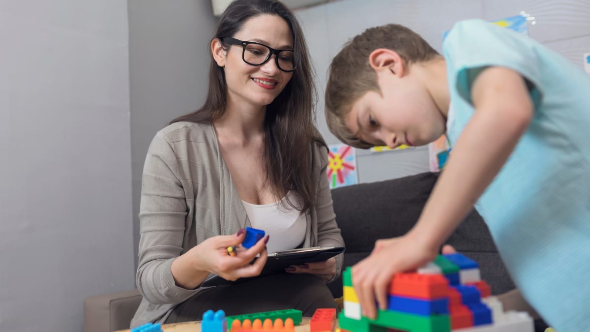 Woman helping child build with toys