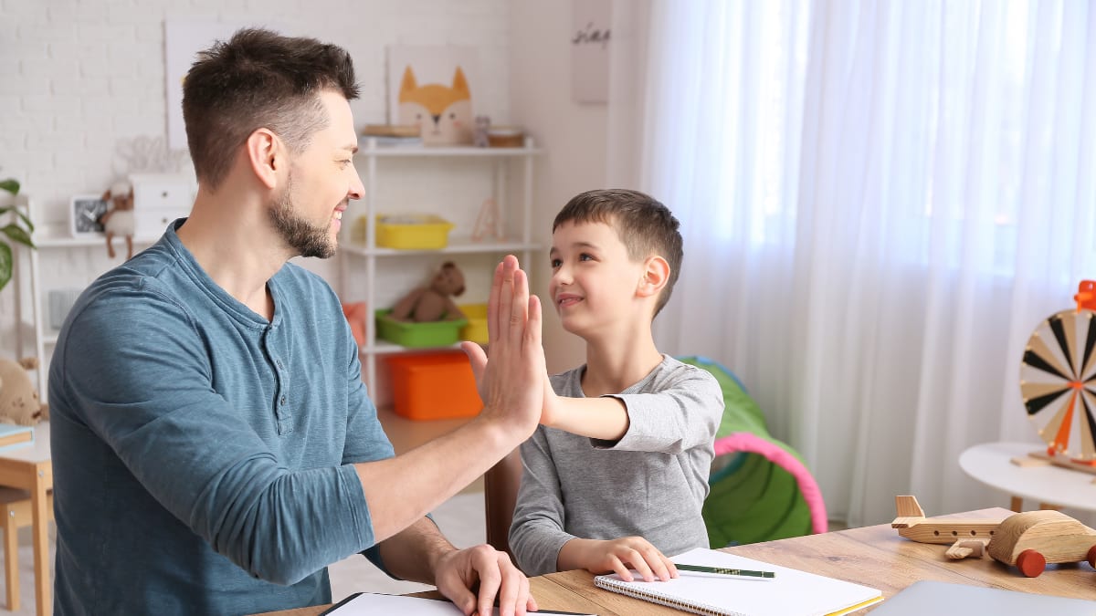 Man high-fiving child while writing notes