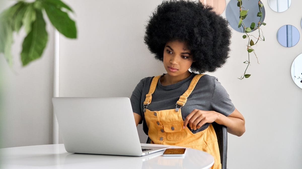 Woman in orange overalls working on a laptop