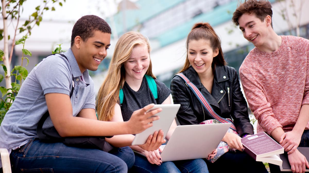 Four students looking at an electronic tablet