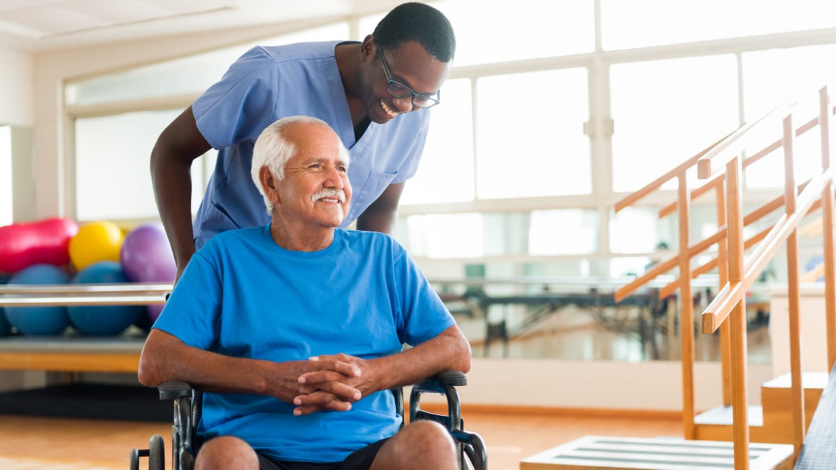 Male nurse pushing an older client in a wheelchair