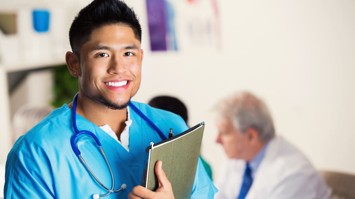Male nurse smiling while holding a patient's health chart