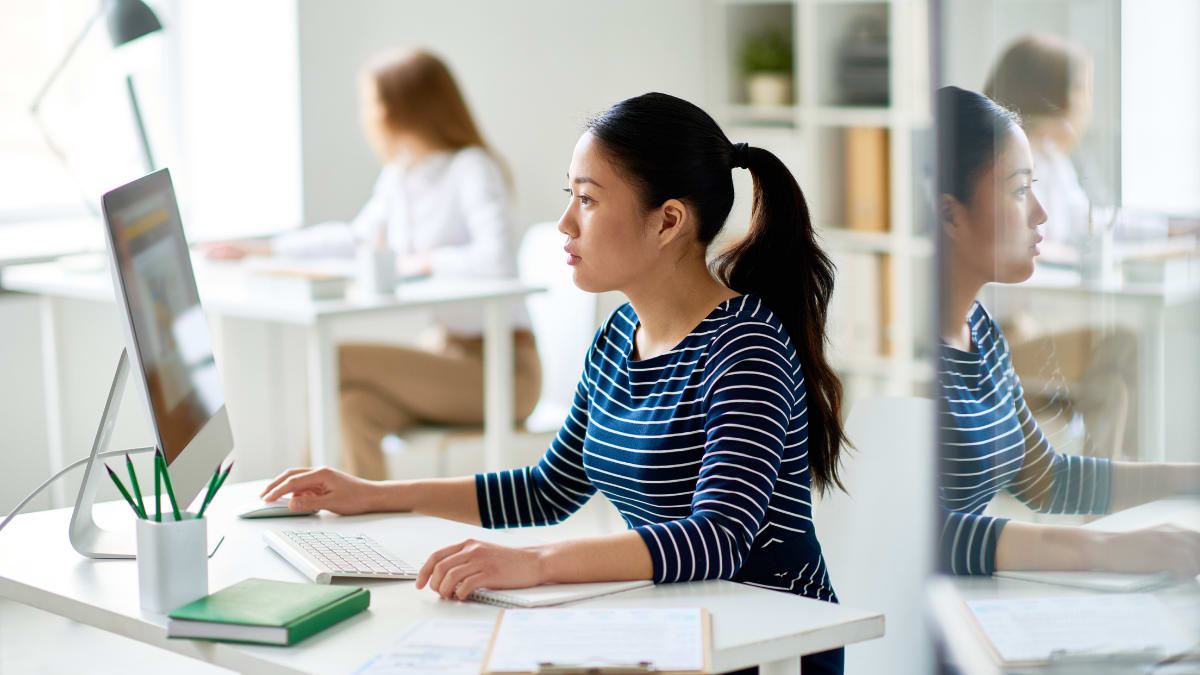 Young female software engineer sitting at her desk in front of a computer
