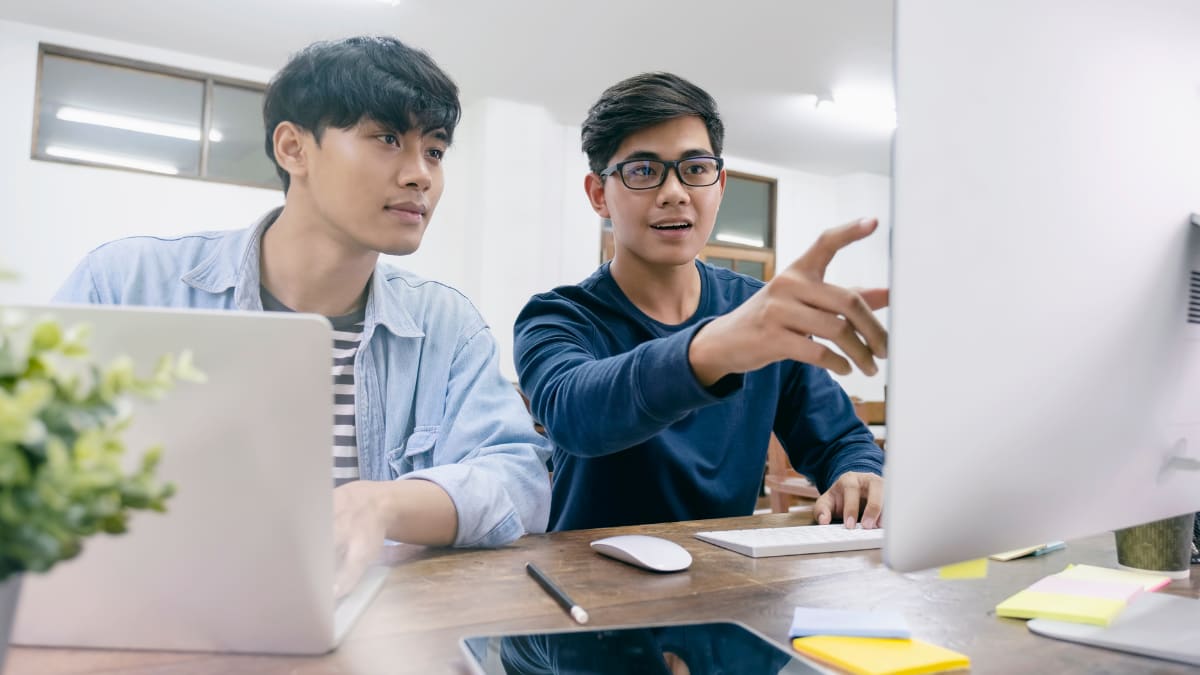 two computer programmers looking at a computer monitor