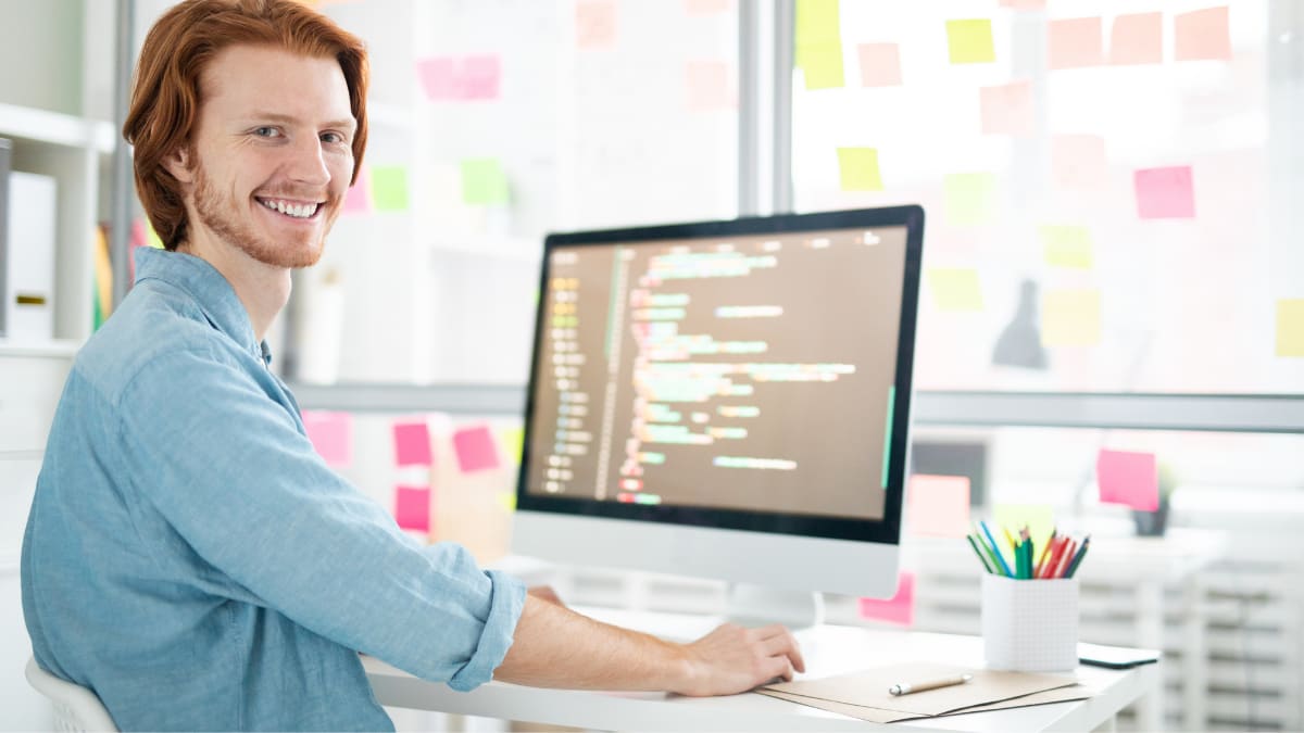 computer programmer sitting at this desk smiling