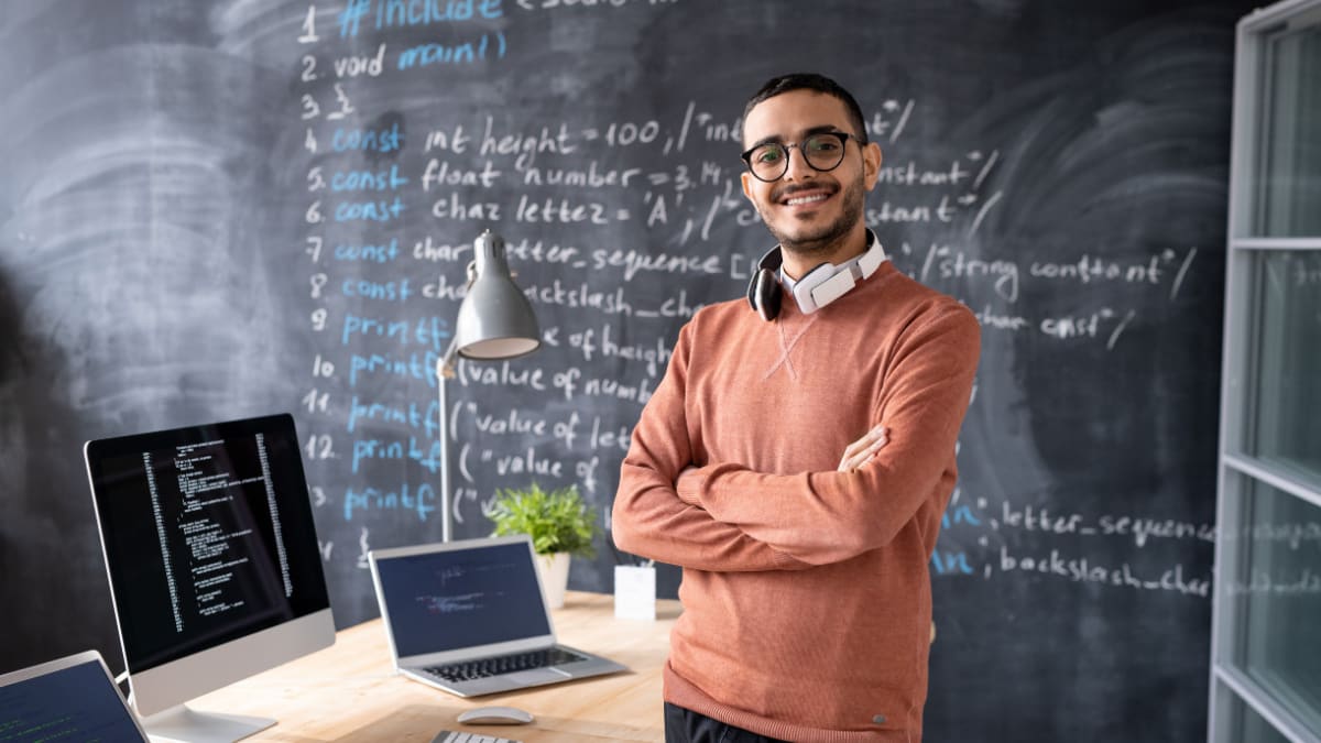 computer programming standing in front of a blackboard with code written on it