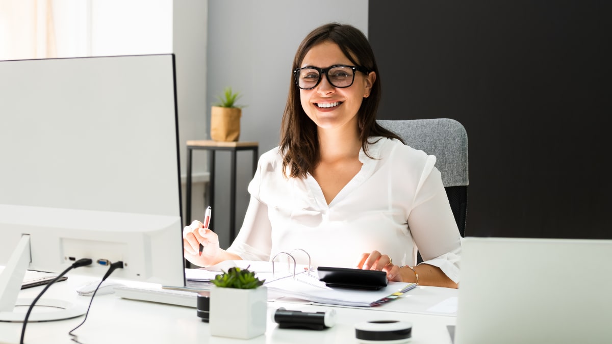 accountant smiling while sitting at her desk working on invoices