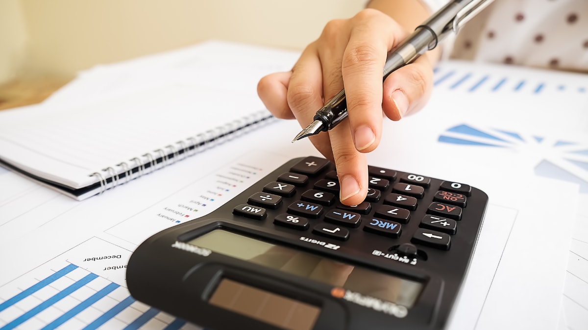 accountant using a calculator to review financial reports