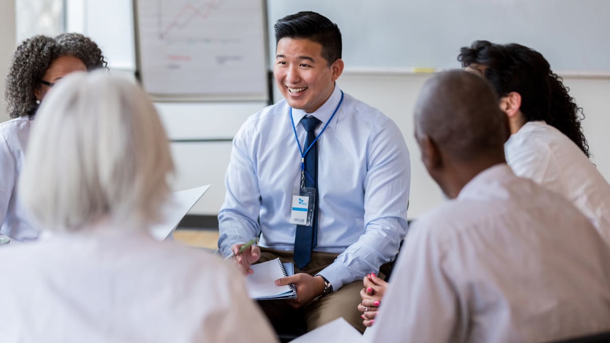 smiling healthcare administrator sitting with a number of medical personnel