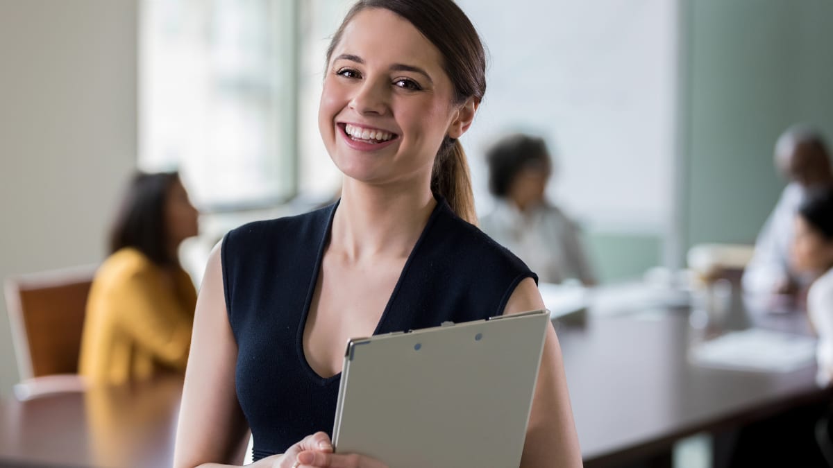 healthcare administrator smiling and holding a clipboard