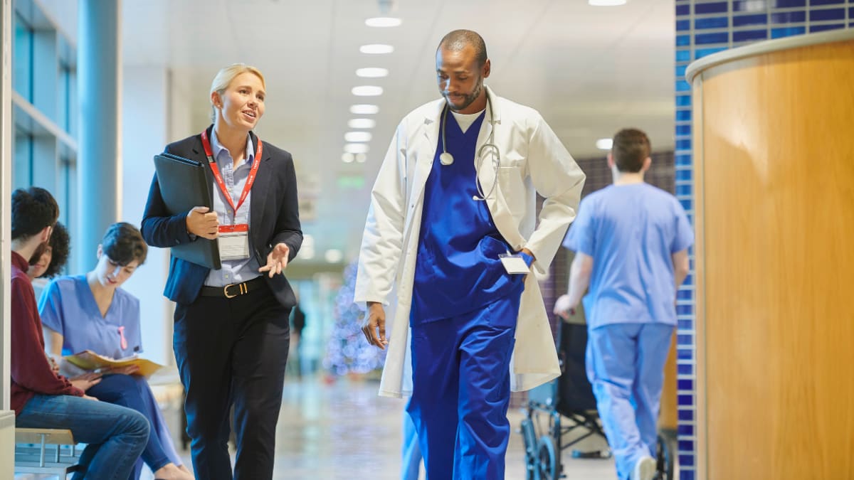 healthcare administrator walks and talks with a doctor