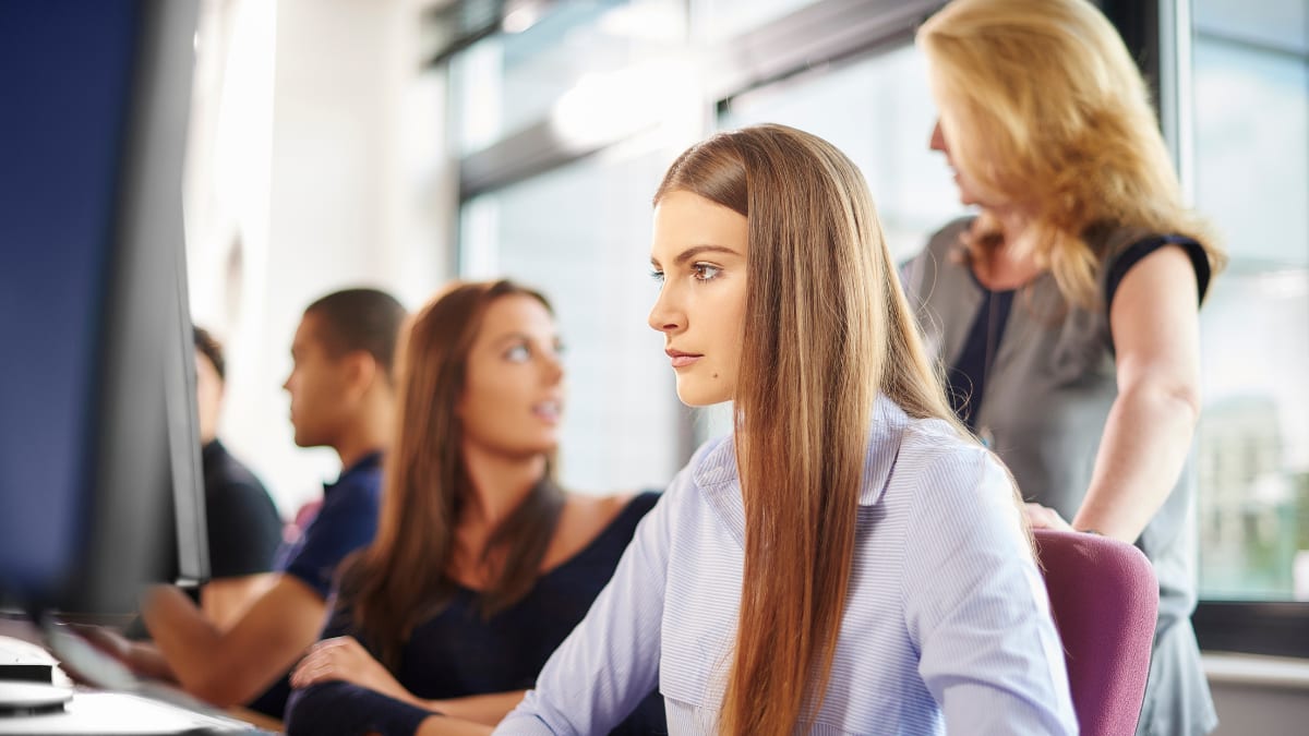 College professor talking with information technology students in a computer lab