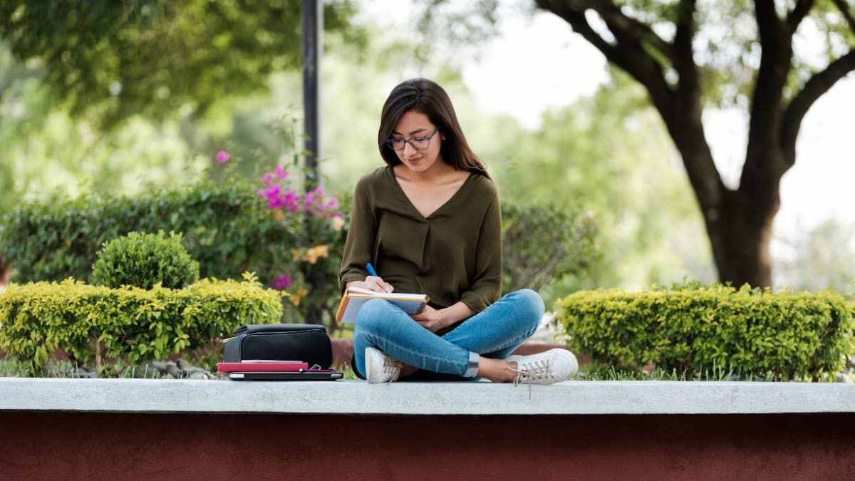 college student enjoying the outdoors while working on coursework
