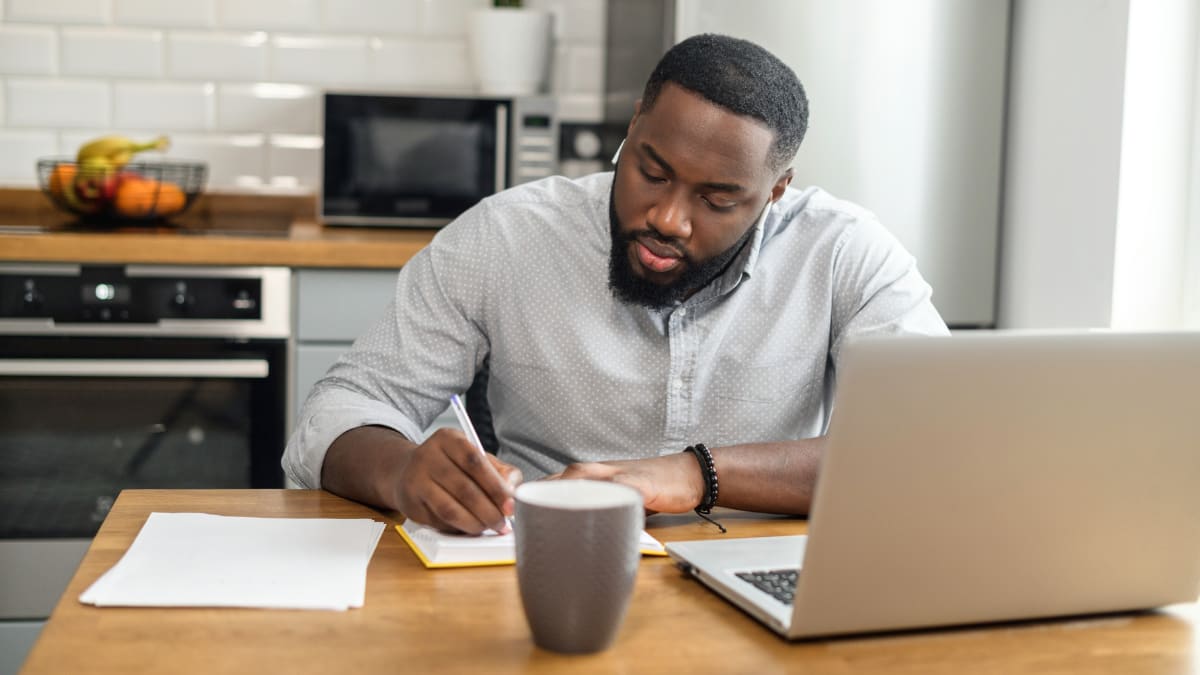 online college student sitting in a kitchen working on an online class