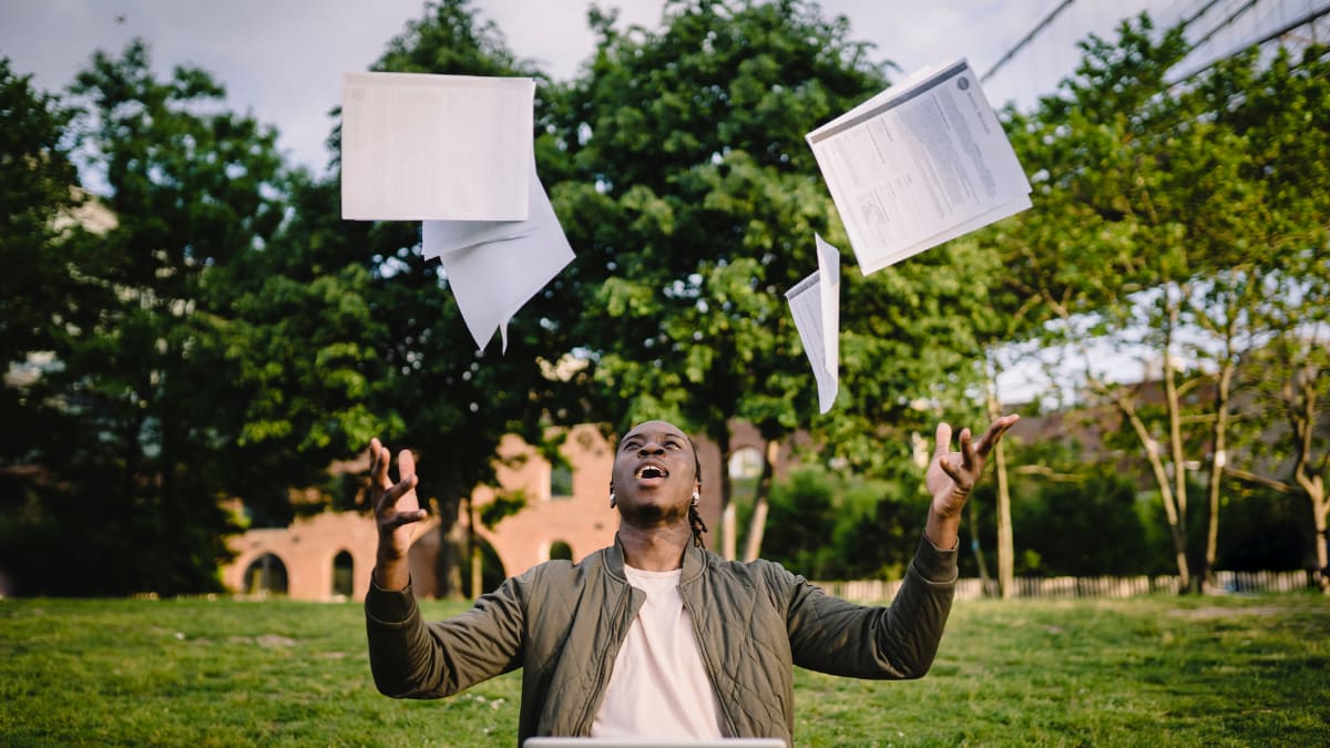 student tossing papers into the air