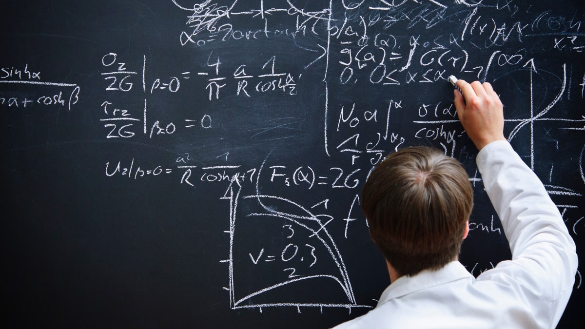 math teacher writing math problems on a chalkboard