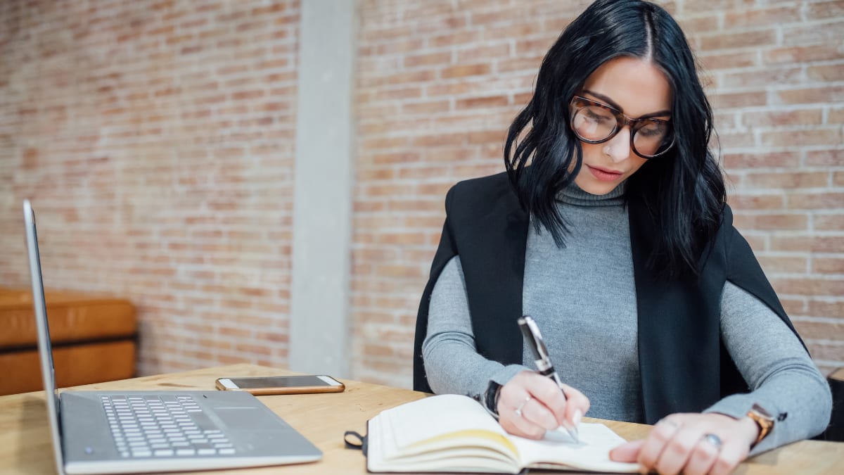 online college student taking notes in a notebook