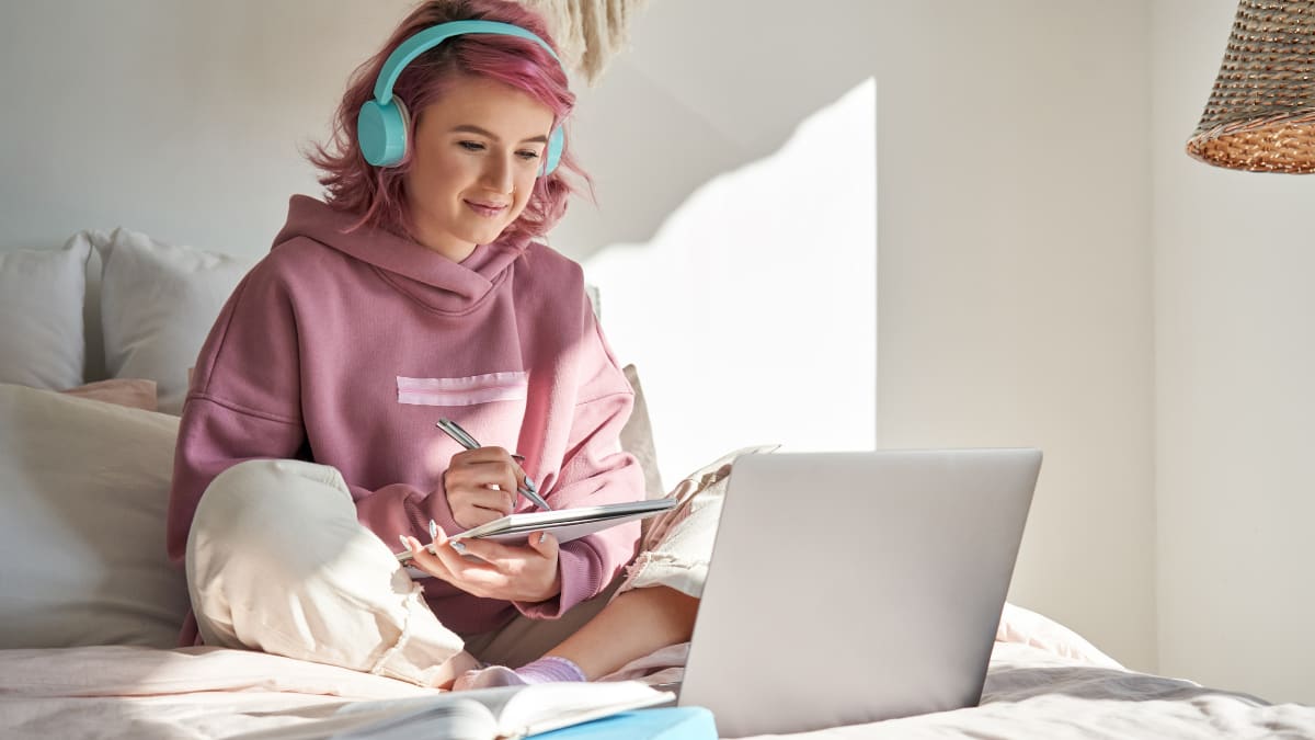 online student working on online courses while sitting in her bedroom
