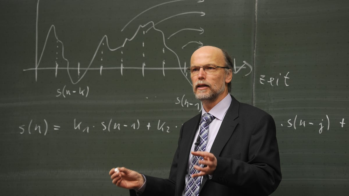 physics lecturer standing in front of a chalkboard