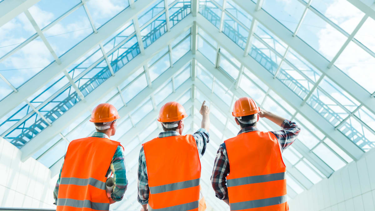 three construction managers look at a glass roof