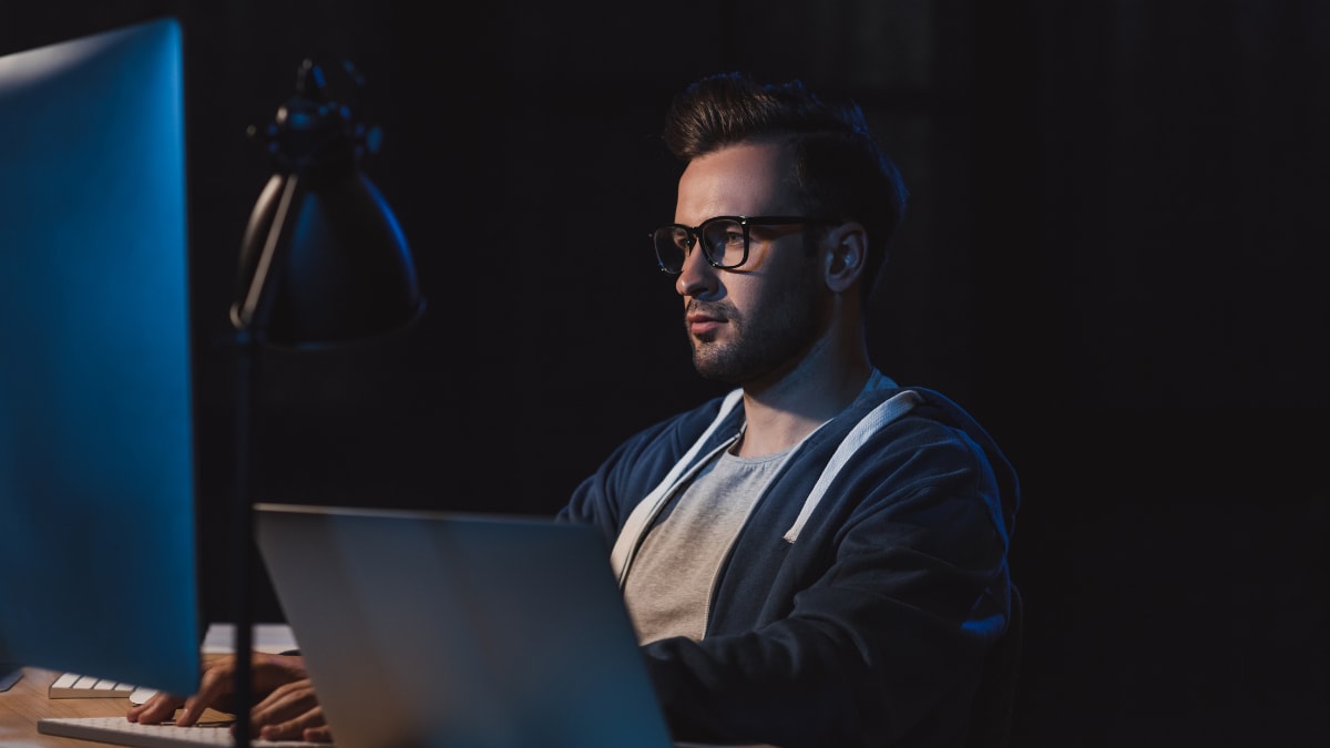 computer programmer working on a desktop in a dark room