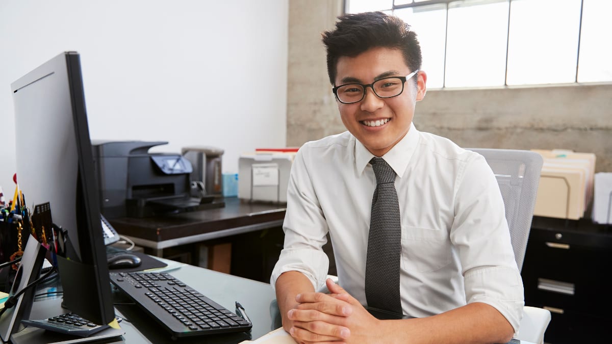 young business professional sitting at a desk in front of a computer