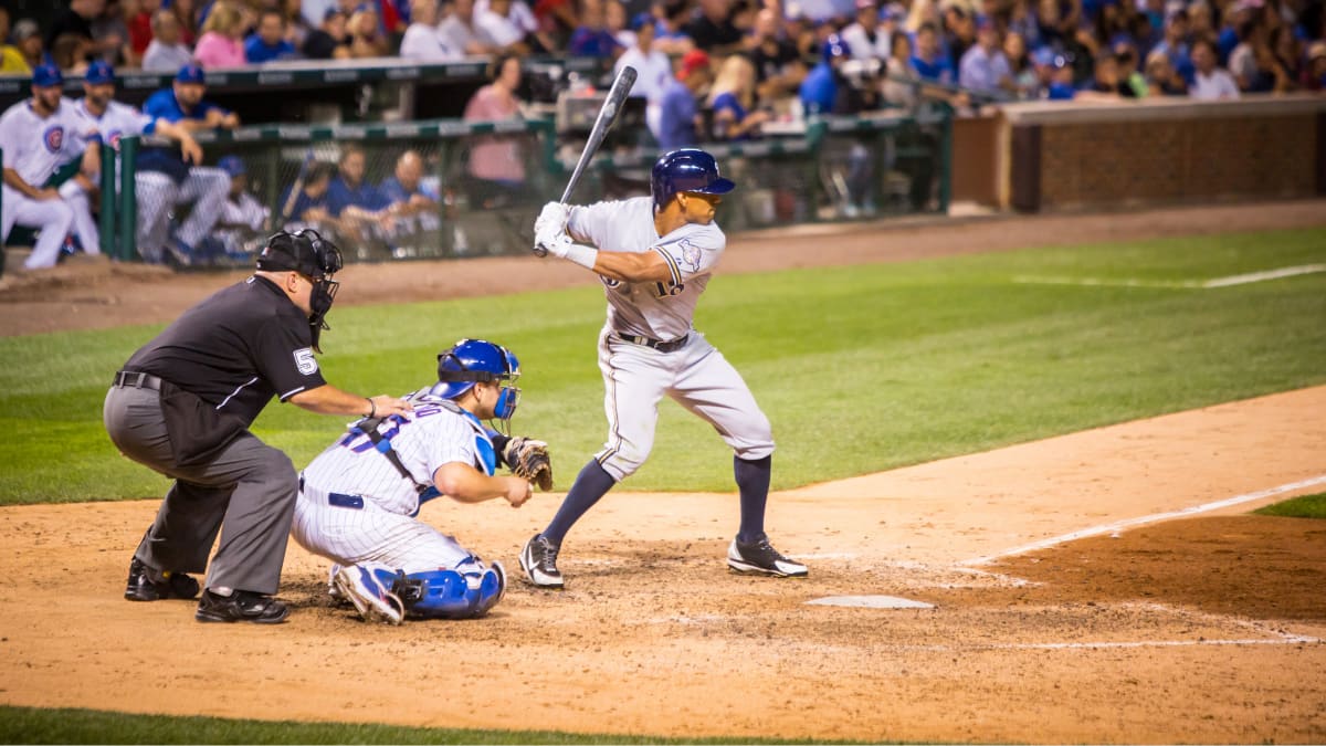 baseball player getting ready for a pitch with a catcher and umpire standing behind him