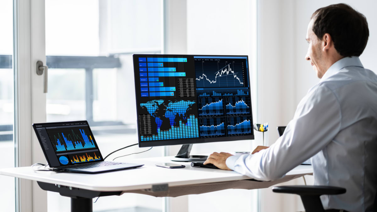 data analyst sitting at a desk with two computers