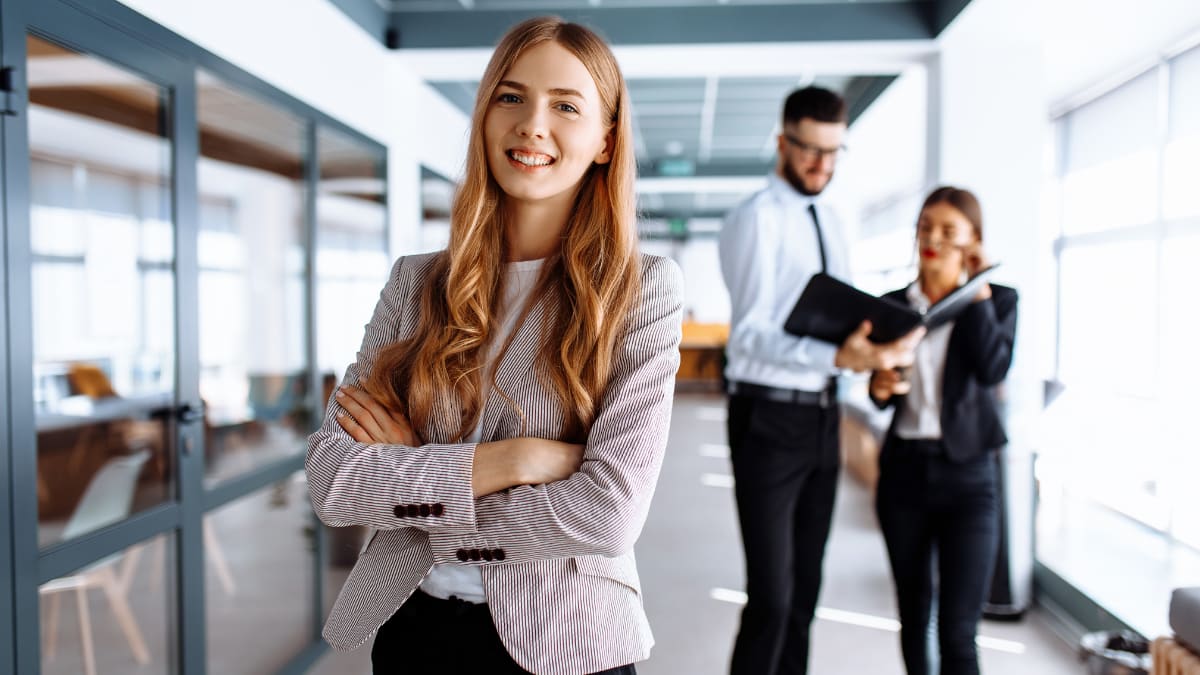 young business professional standing in an office with coworkers