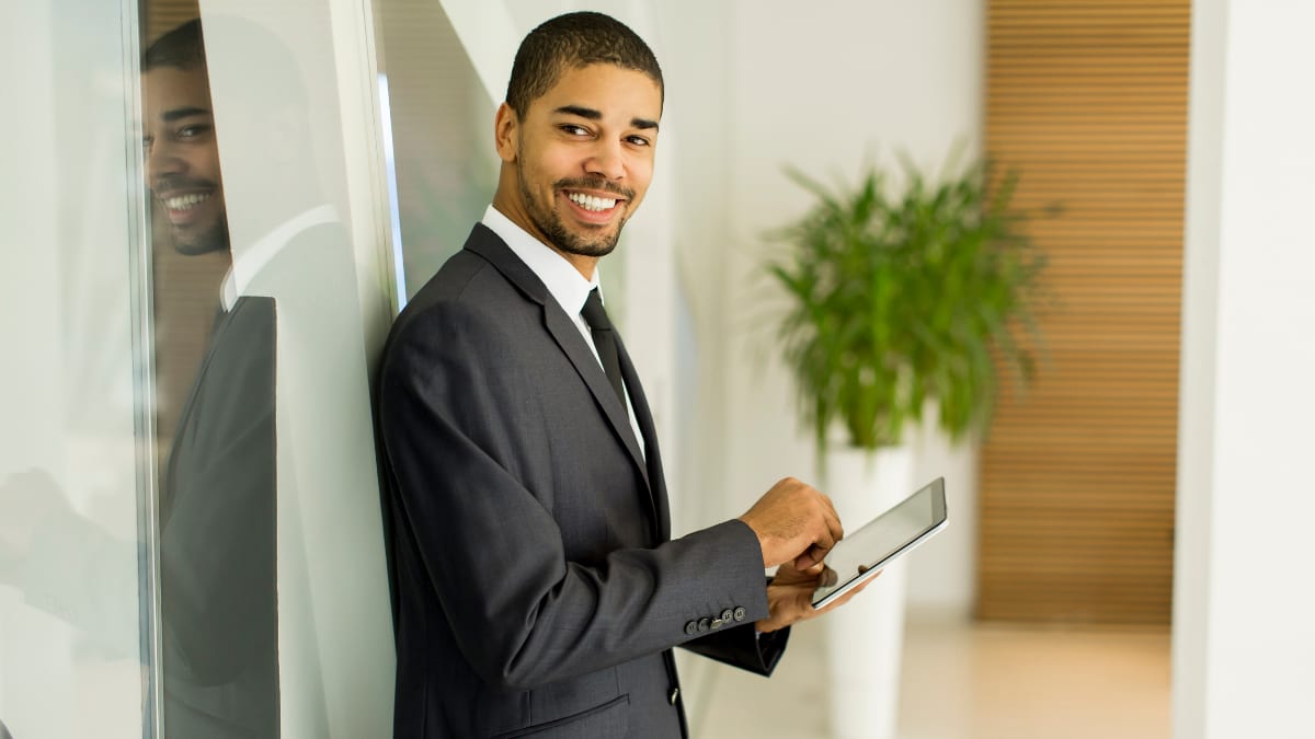 young business professional standing in an office holding a tablet