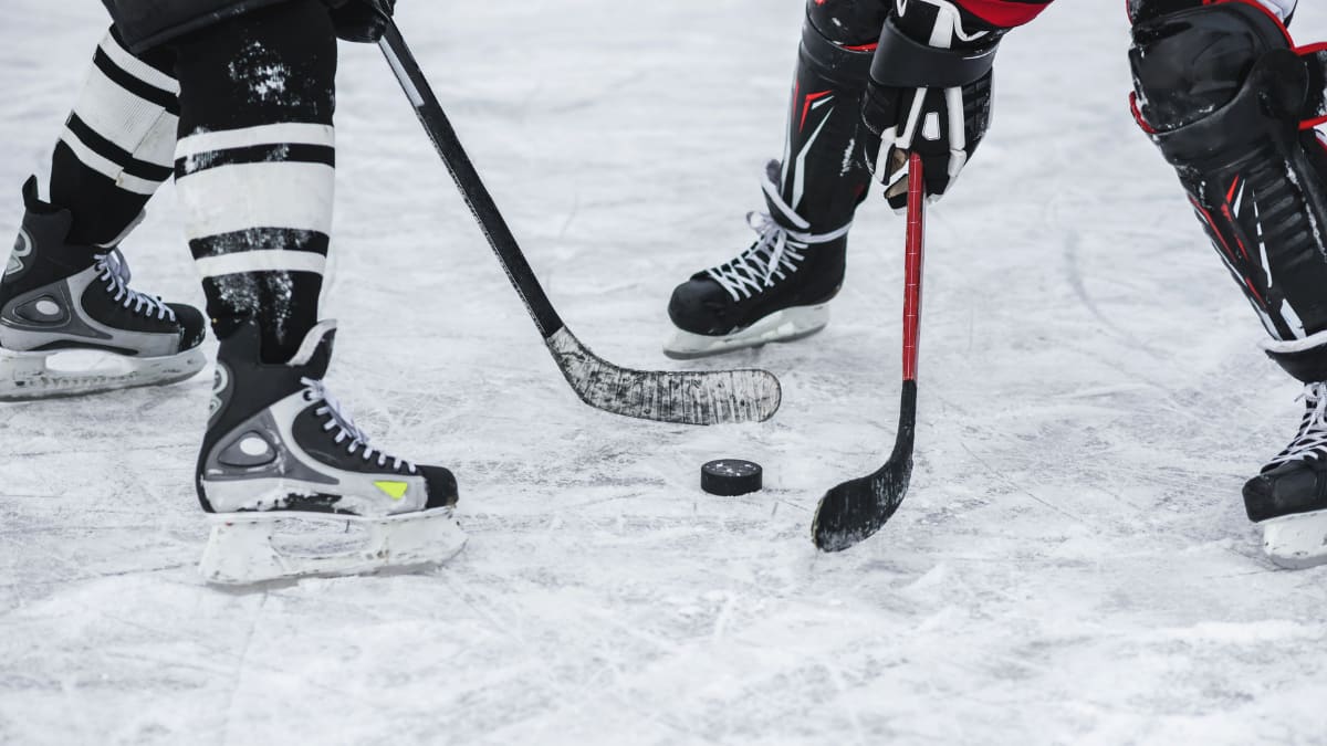 two hockey players holding hockey sticks with a puck between them