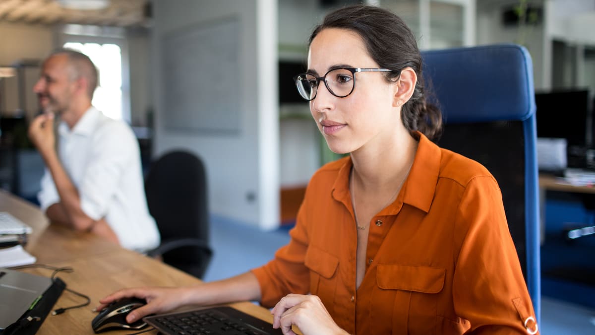 software programmer sitting at a desk in front of a large computer monitor