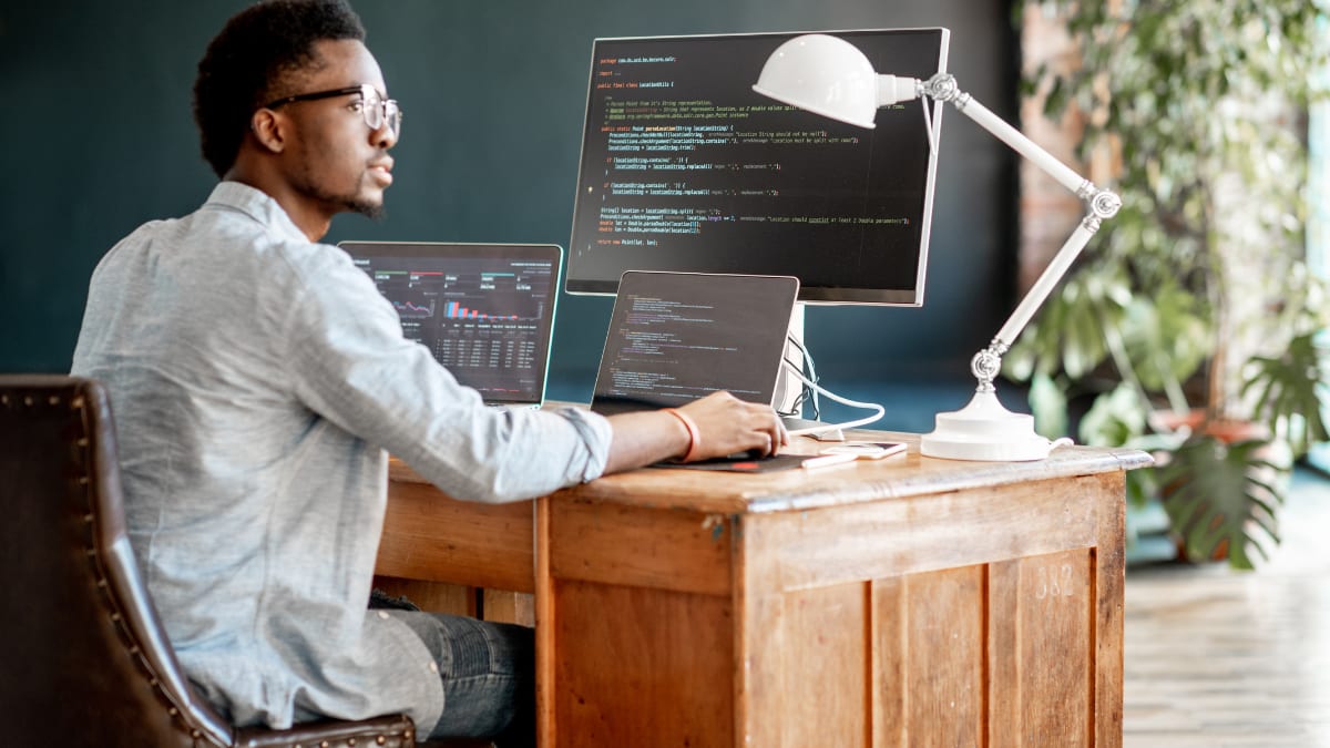 online computer science student sitting in front of a number of computers