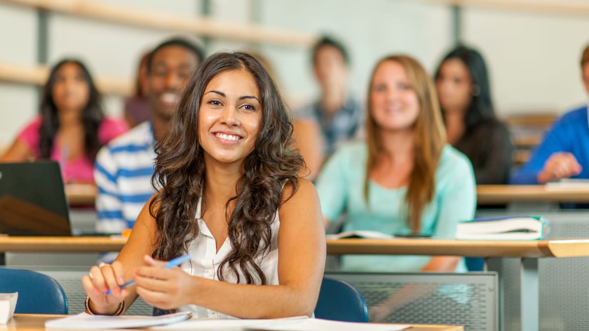 smiling college student sitting in a college classroom