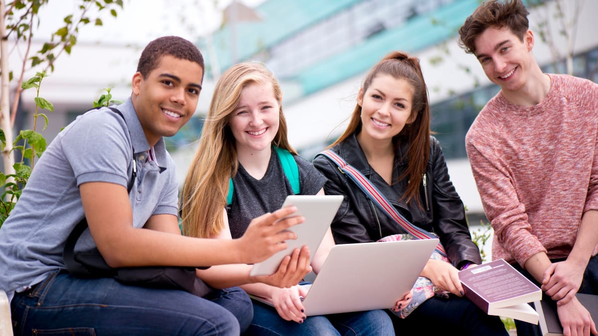 happy college students sitting outside on a college campus