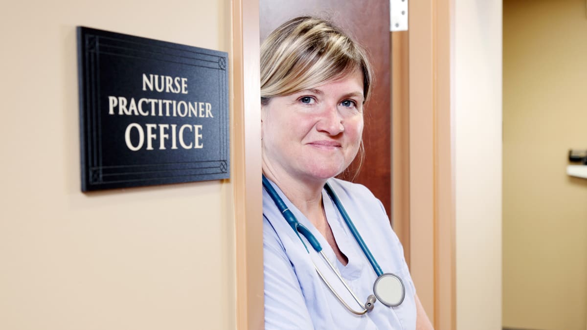 a nurse practitioner standing in the doorway of her office