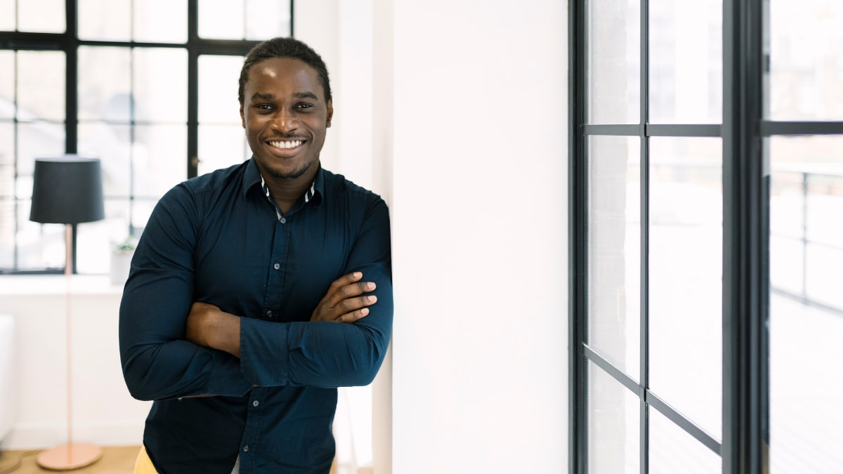 young college student standing in an office with his arms crossed