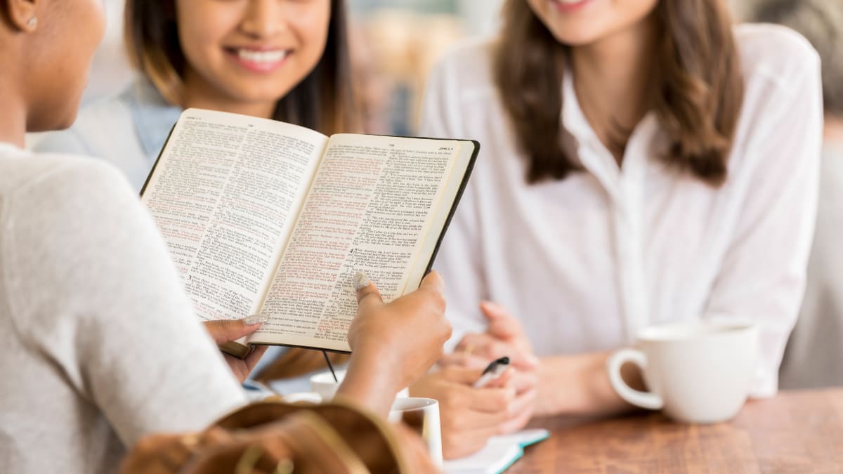 a student reading the Bible to two other students