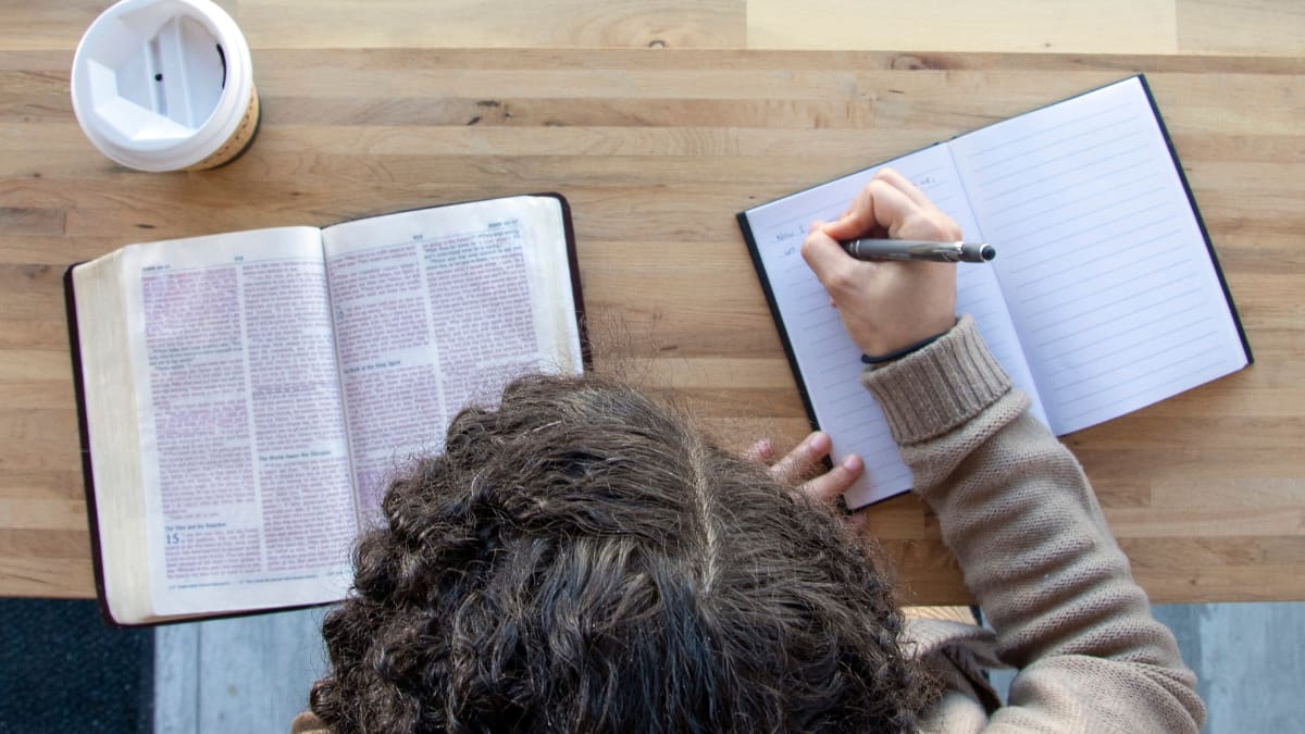 student studying the Bible and writing in a journal