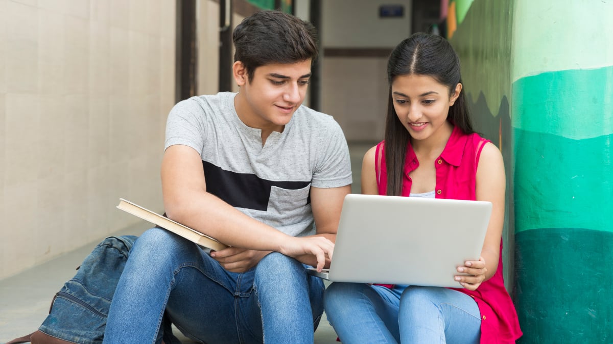 two college students sitting together looking at a laptop