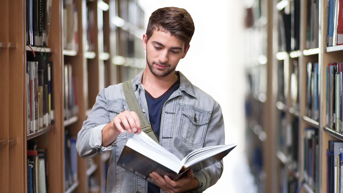 college student in a library holding a library book