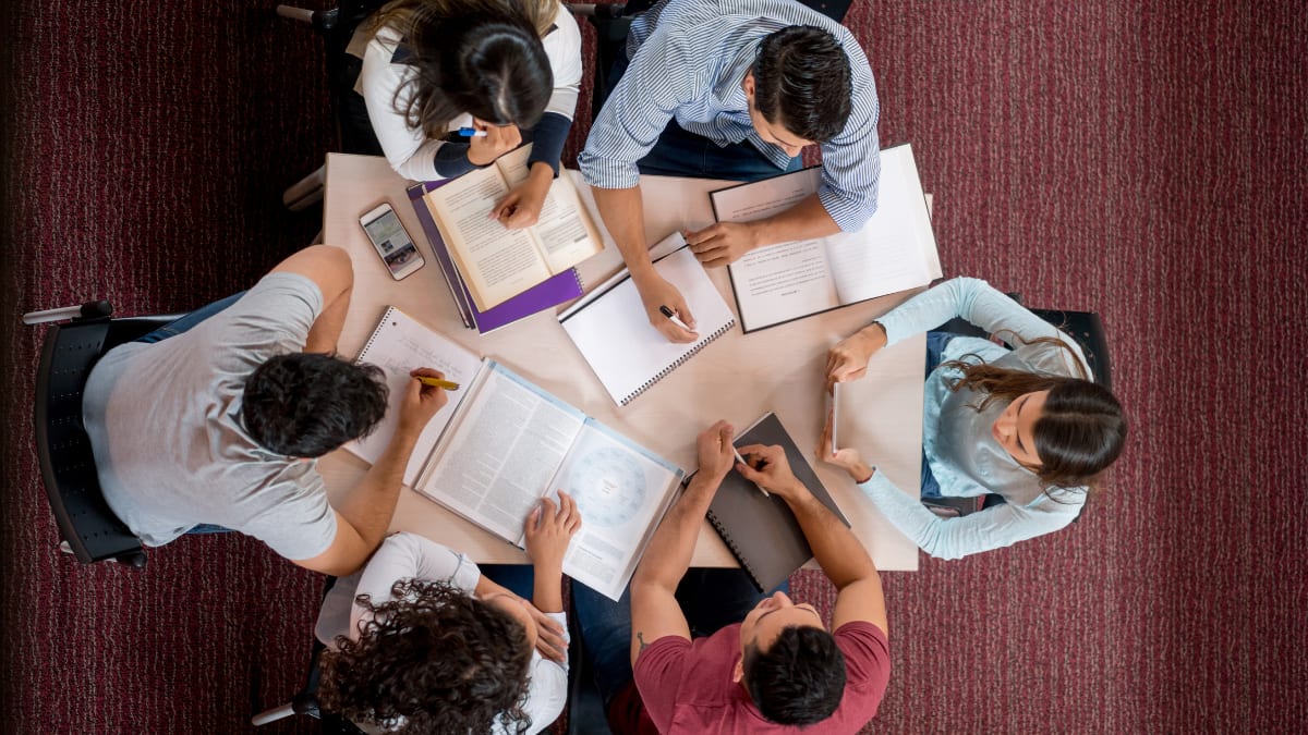 a group of college students sitting around a table studying together