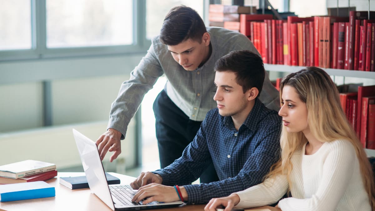 three students looking at a laptop