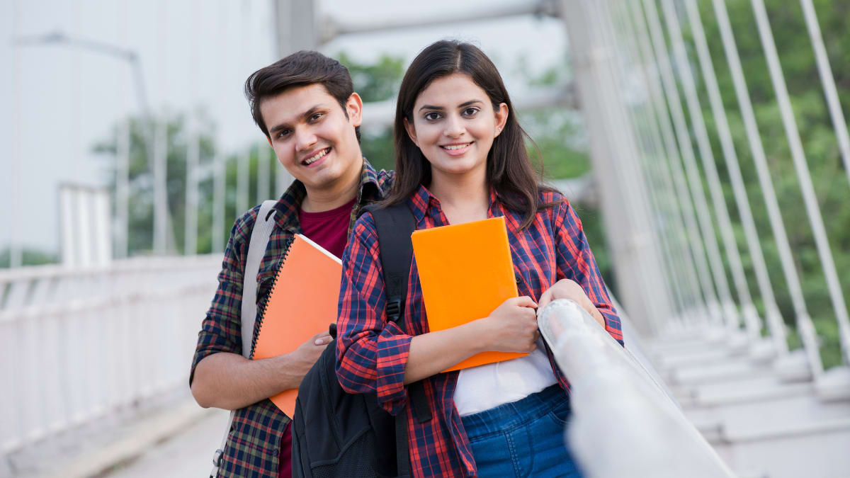 two smiling college students standing together outside